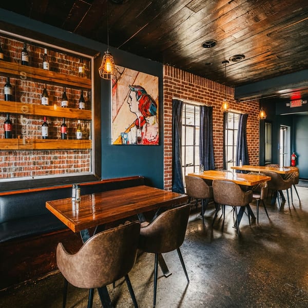 Cozy restaurant interior with brick walls, dark wood tables, leather chairs, and a wine bottle display.